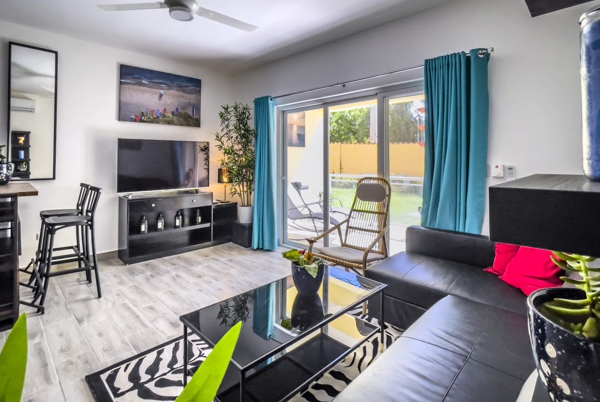 buyDRproperty Modern living room of a one bedroom condo in Sosua with black leather sofa and zebra rug. Sosua Real Estate
