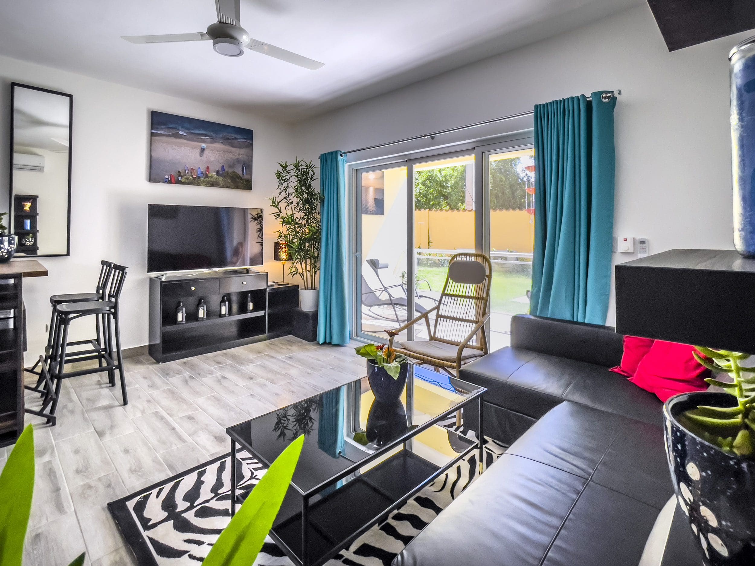 buyDRproperty Modern living room of a one bedroom condo in Sosua with black leather sofa and zebra rug. Sosua Real Estate