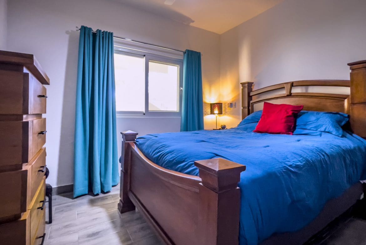 buyDRproperty One bedroom condo bedroom with blue bedding and wooden furniture. Sosua Real Estate