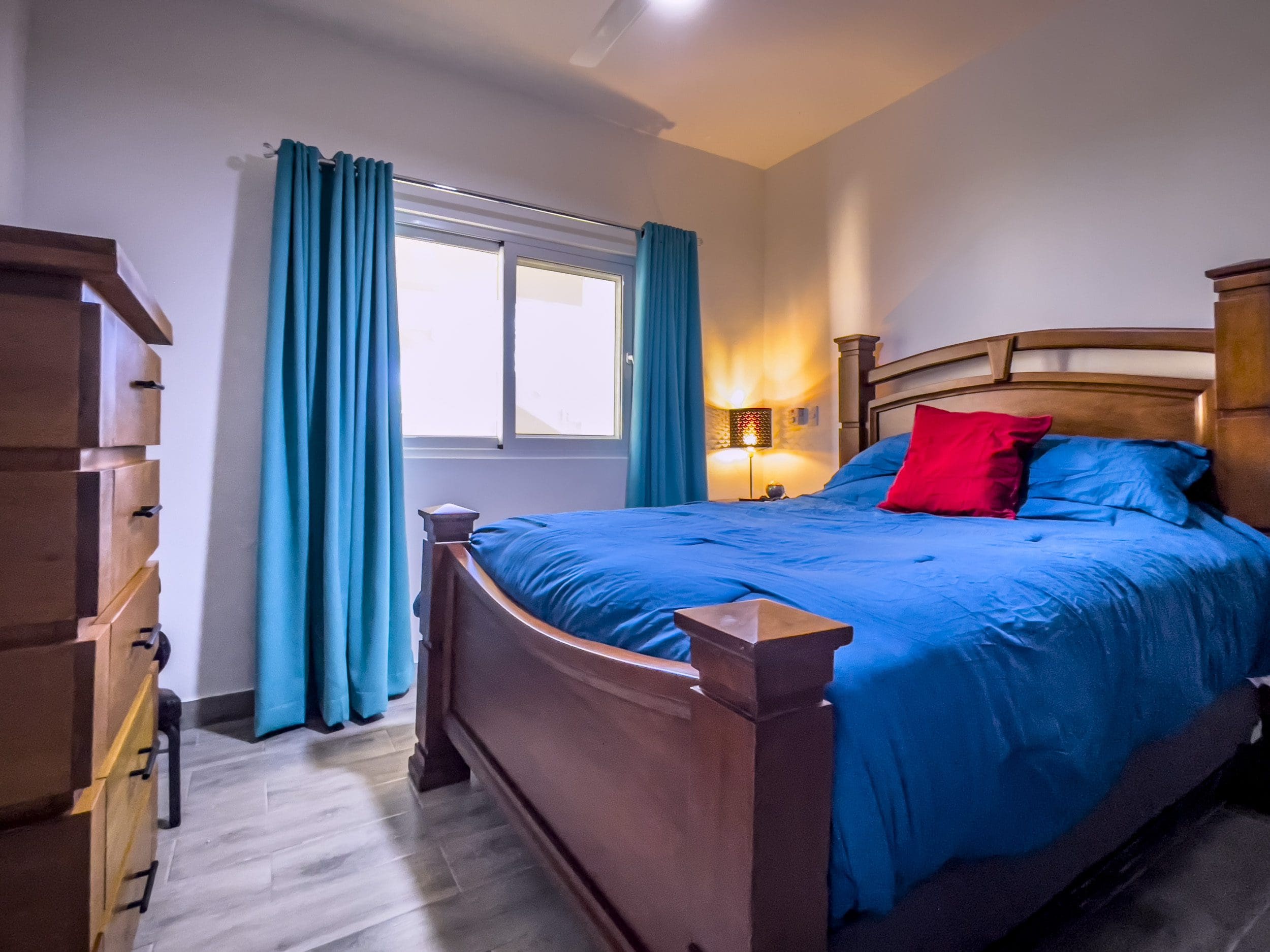 buyDRproperty One bedroom condo bedroom with blue bedding and wooden furniture. Sosua Real Estate