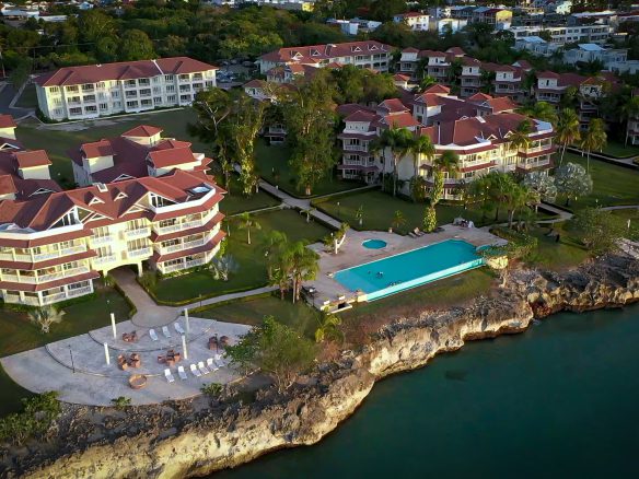 buyDRproperty Coastal resort with red-tiled roofs, swimming pool, and rocky coastline. Sosua Real Estate