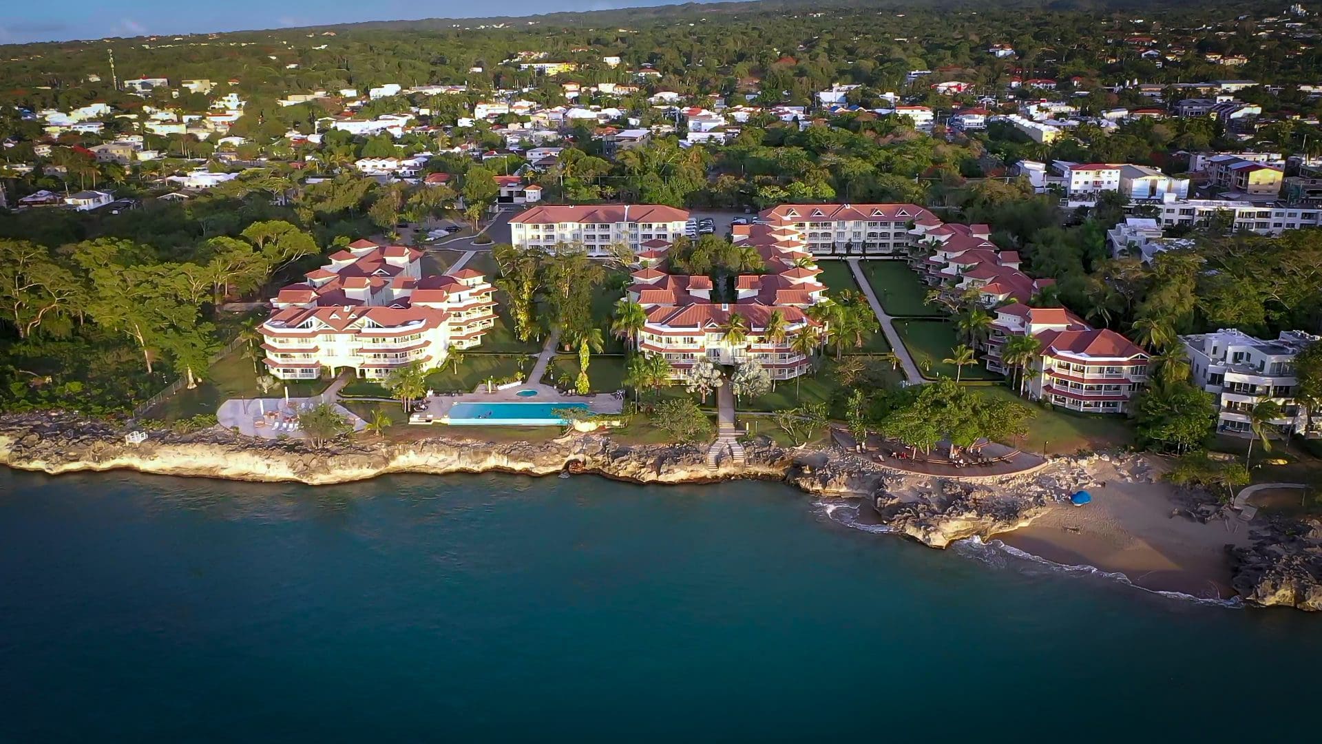 buyDRproperty Aerial view of a 2-bedroom condo in Hispaniola Beach, showcasing resort buildings, pool, and beach. Sosua Real Estate
