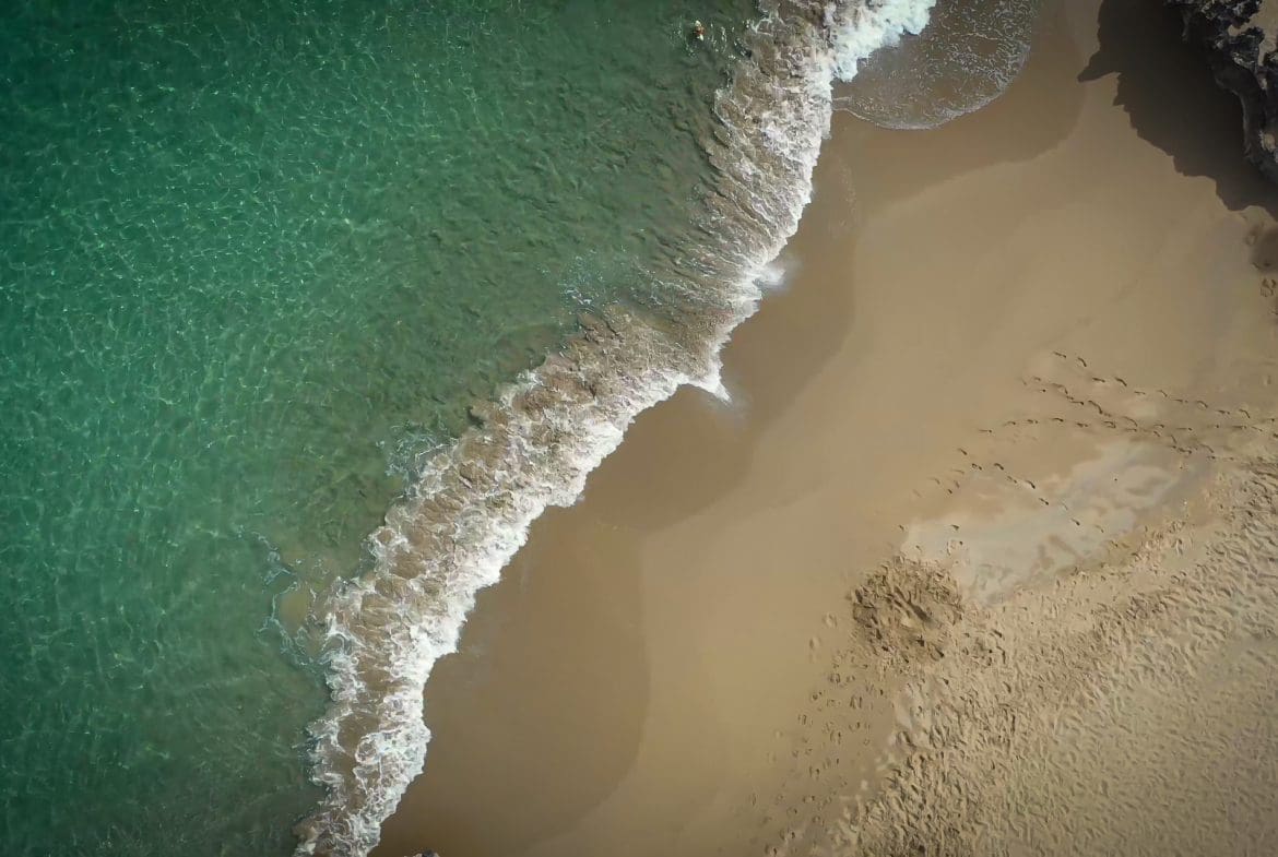 buyDRproperty Aerial view of turquoise water meeting sandy beach. Sosua Real Estate