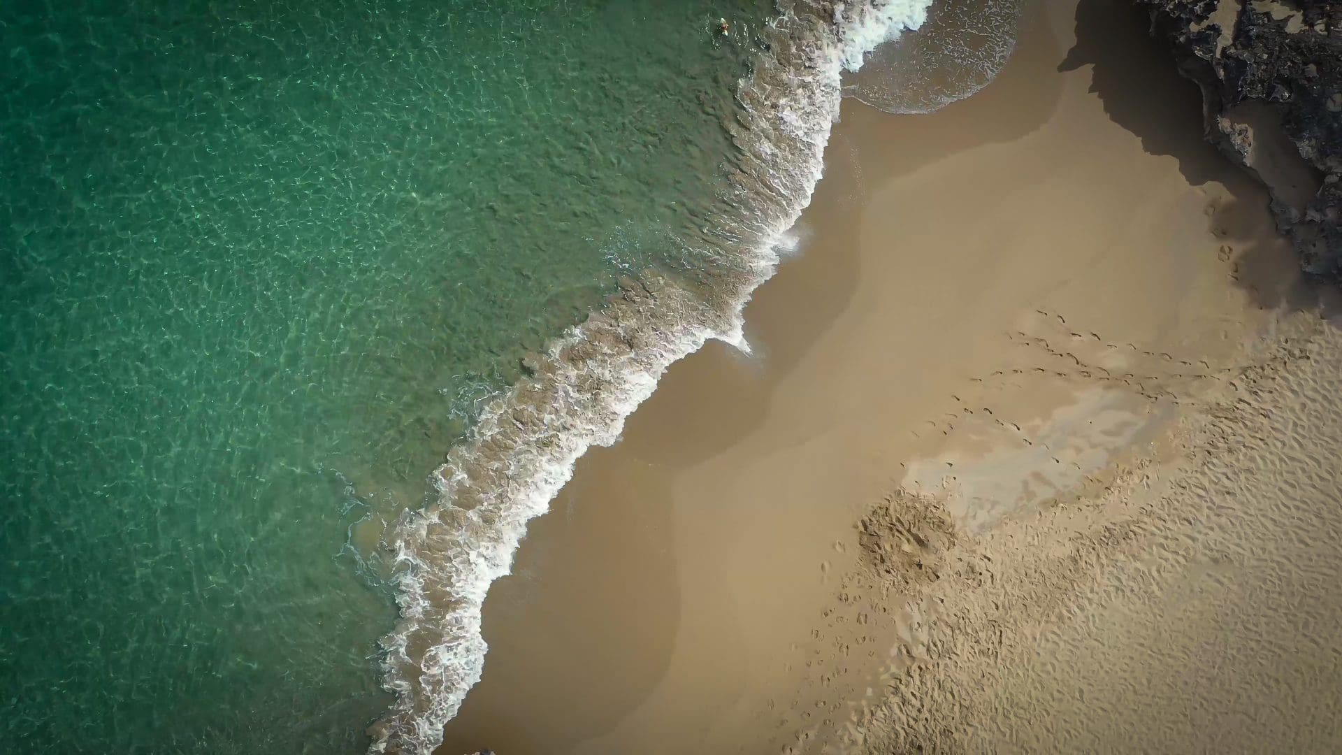 buyDRproperty Aerial view of a beach with clear turquoise water and a sandy shore. Sosua Real Estate