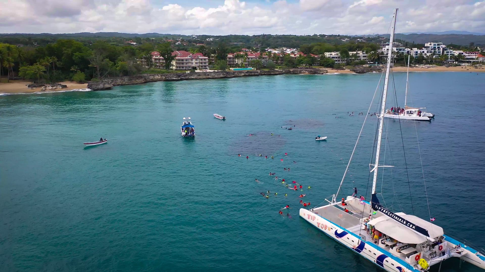buyDRproperty Boats and snorkelers in turquoise water near a beach Sosua Real Estate