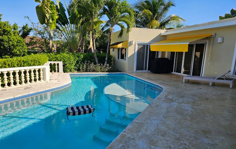 buyDRproperty Casa Linda Villa with a pool, palm trees, and a yellow awning Sosua Real Estate