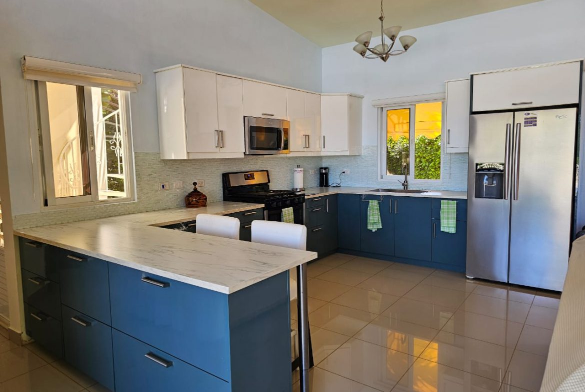 buyDRproperty Modern kitchen in a Casa Linda Villa with blue and white cabinets and stainless steel appliances. Sosua Real Estate
