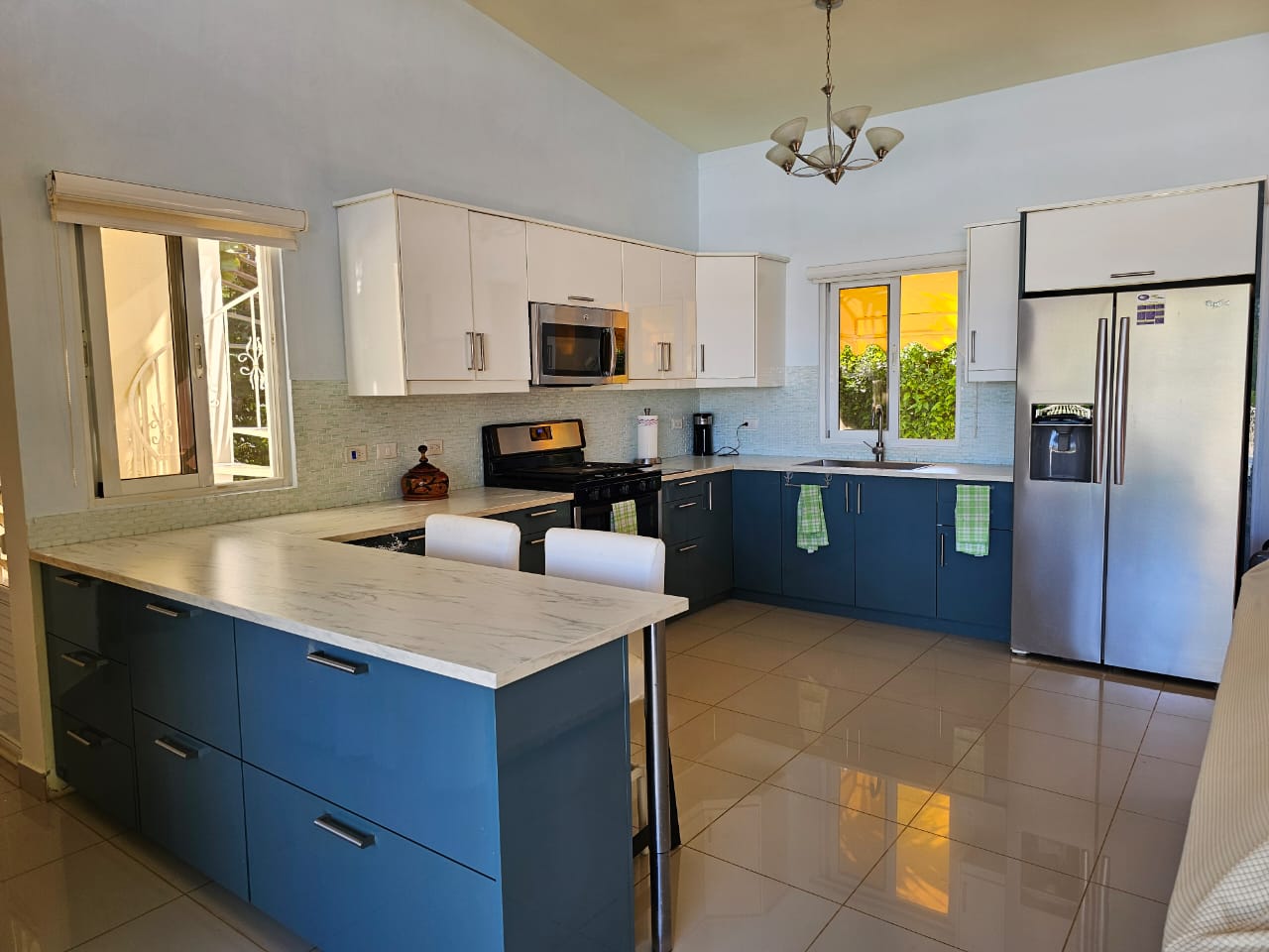 buyDRproperty Modern kitchen in a Casa Linda Villa with blue and white cabinets and stainless steel appliances. Sosua Real Estate