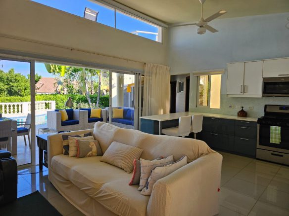 buyDRproperty Casa Linda Villa living room with open doors to a pool and outdoor seating. Sosua Real Estate