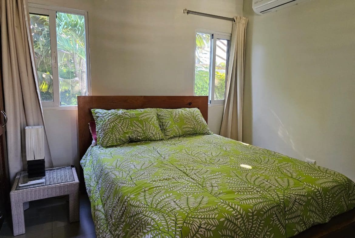 buyDRproperty Bedroom in a Casa Linda Villa with green fern bedding and a wooden headboard. Sosua Real Estate