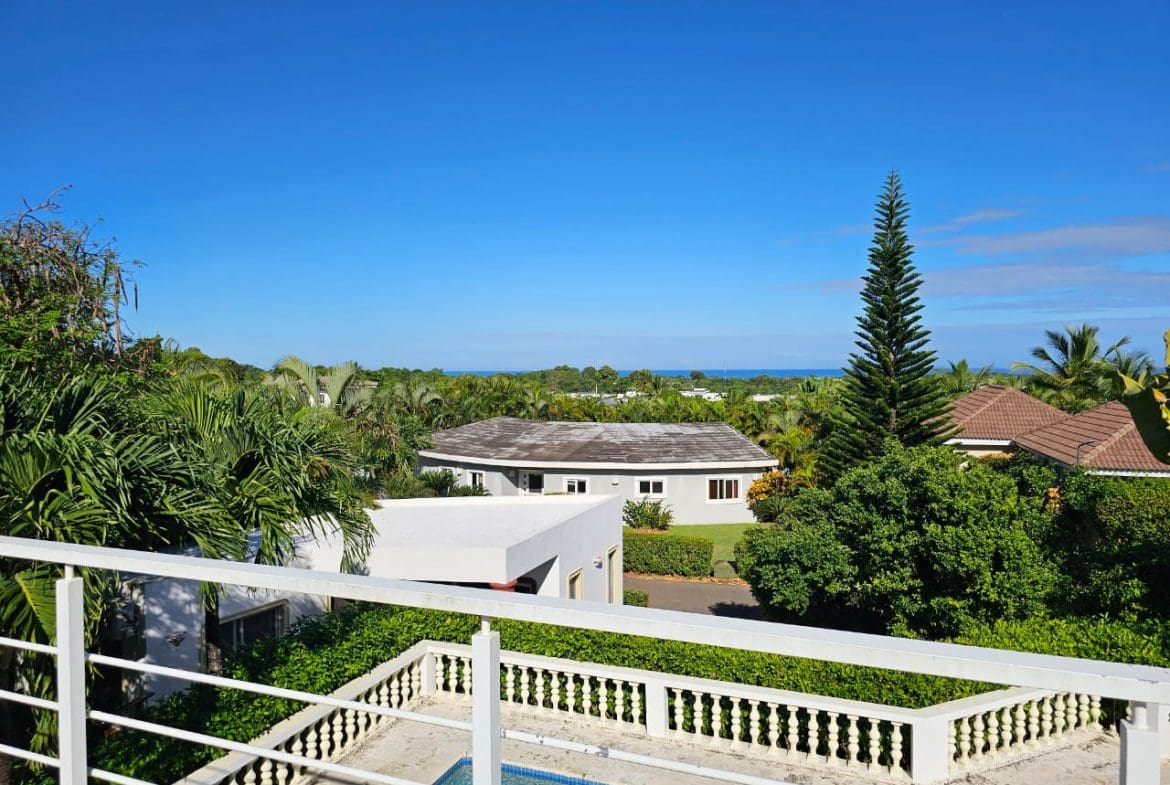buyDRproperty View of a Casa Linda Villa with pool, lush greenery, and ocean in the distance. Sosua Real Estate