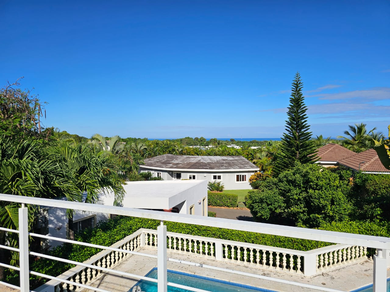 buyDRproperty View of a Casa Linda Villa with pool, lush greenery, and ocean in the distance. Sosua Real Estate