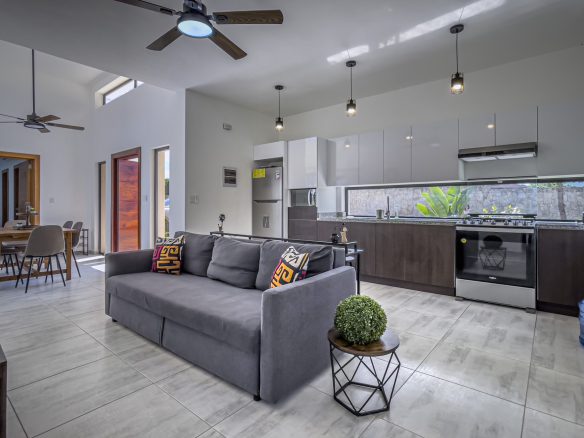 buyDRproperty Modern 3 bedroom villa living room with gray sofa and kitchen in the background. Sosua Real Estate