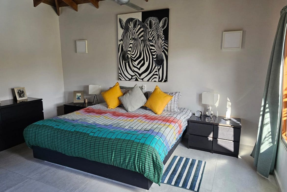 buyDRproperty Bedroom interior with zebra art, colorful bedspread, and ocean views from the villa for sale. Sosua Real Estate