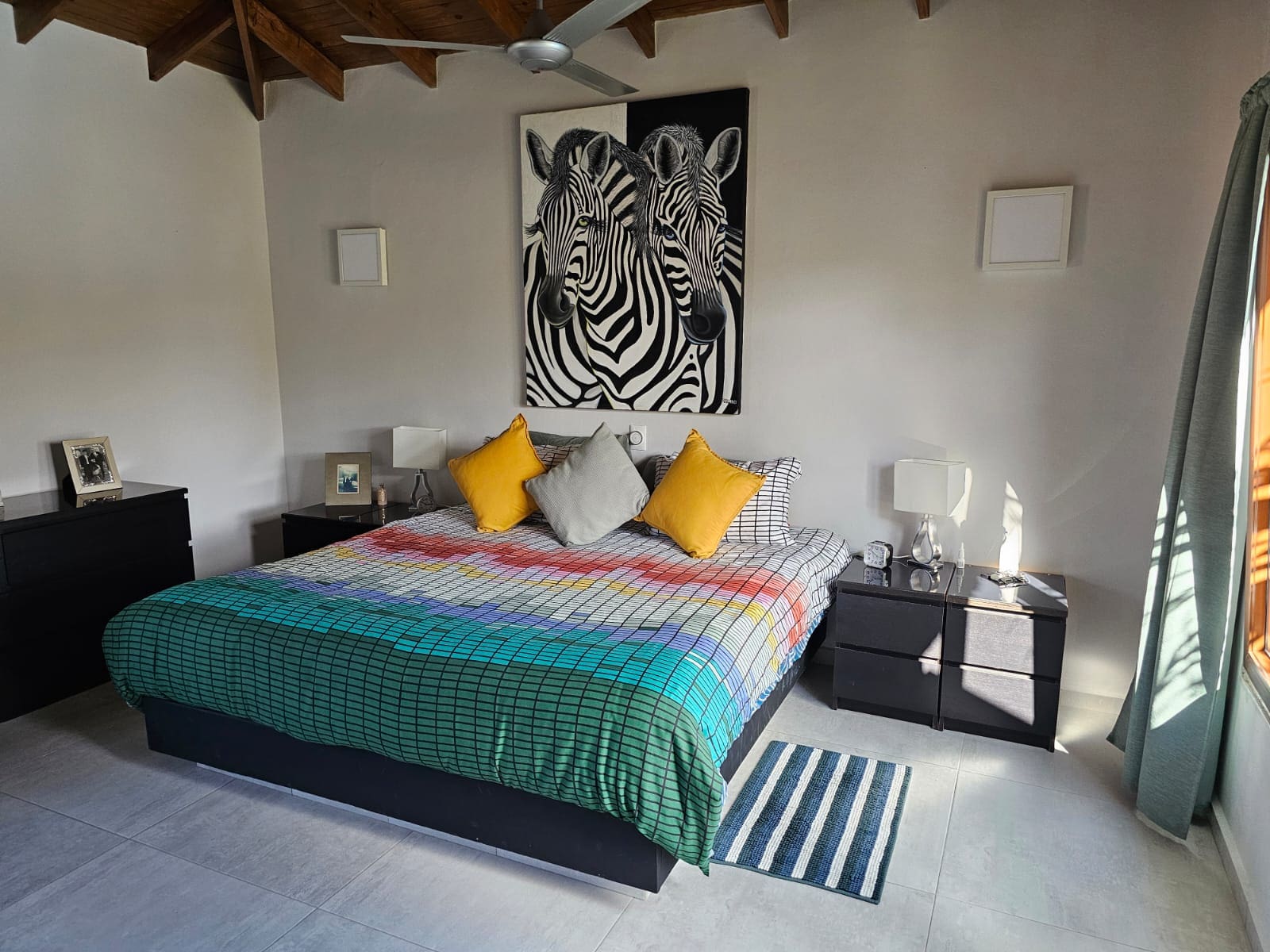 buyDRproperty Bedroom interior with zebra art, colorful bedspread, and ocean views from the villa for sale. Sosua Real Estate