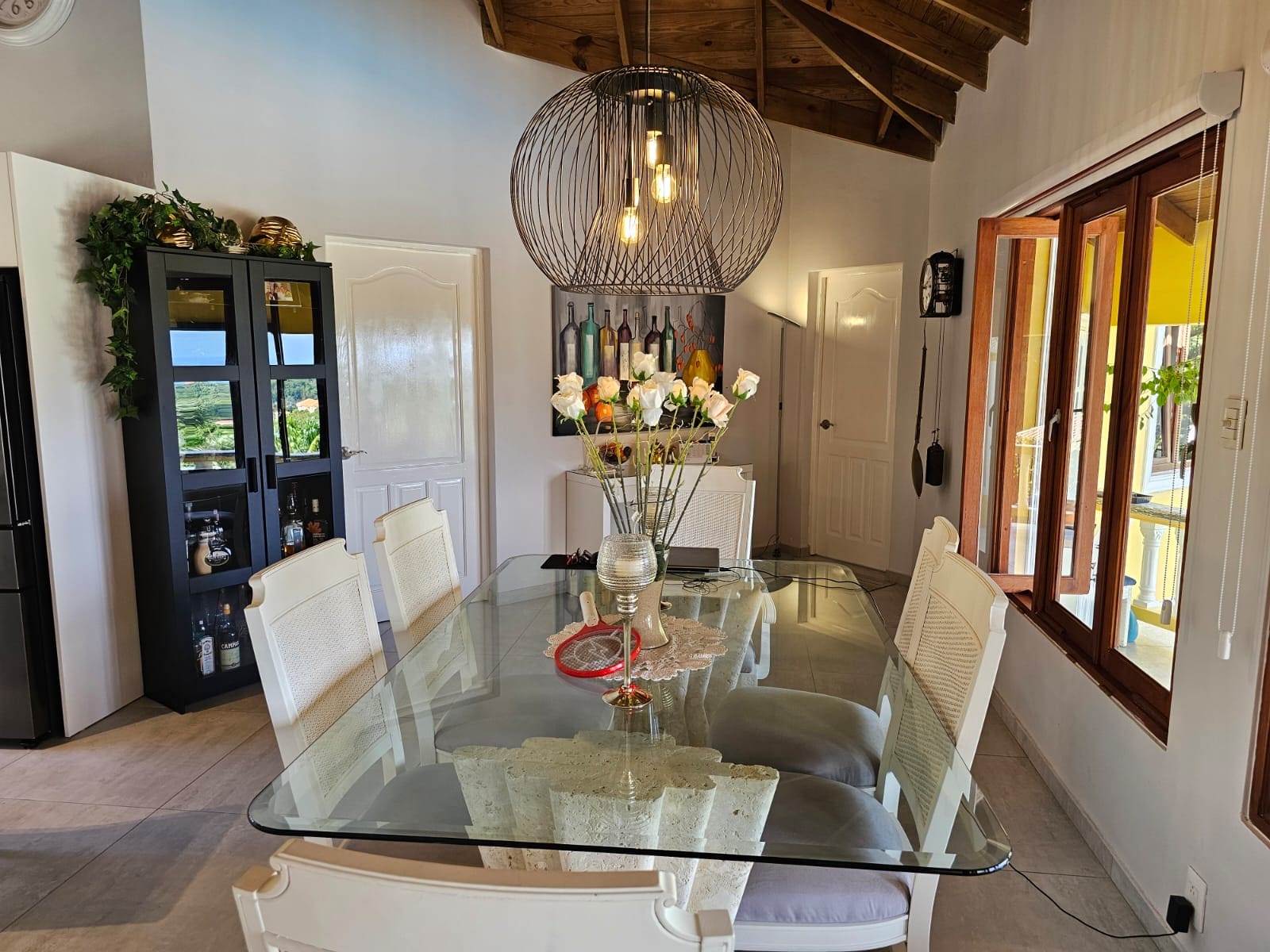 buyDRproperty Dining area in luxury villa with ocean views, featuring glass table, white chairs, and modern lighting. Sosua Real Estate