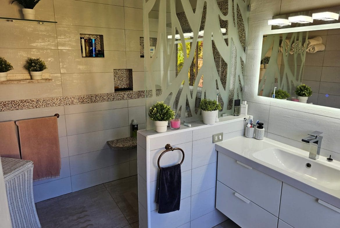 buyDRproperty Modern bathroom with unique glass partition and ocean views reflected in the mirror, Villa For Sale. Sosua Real Estate