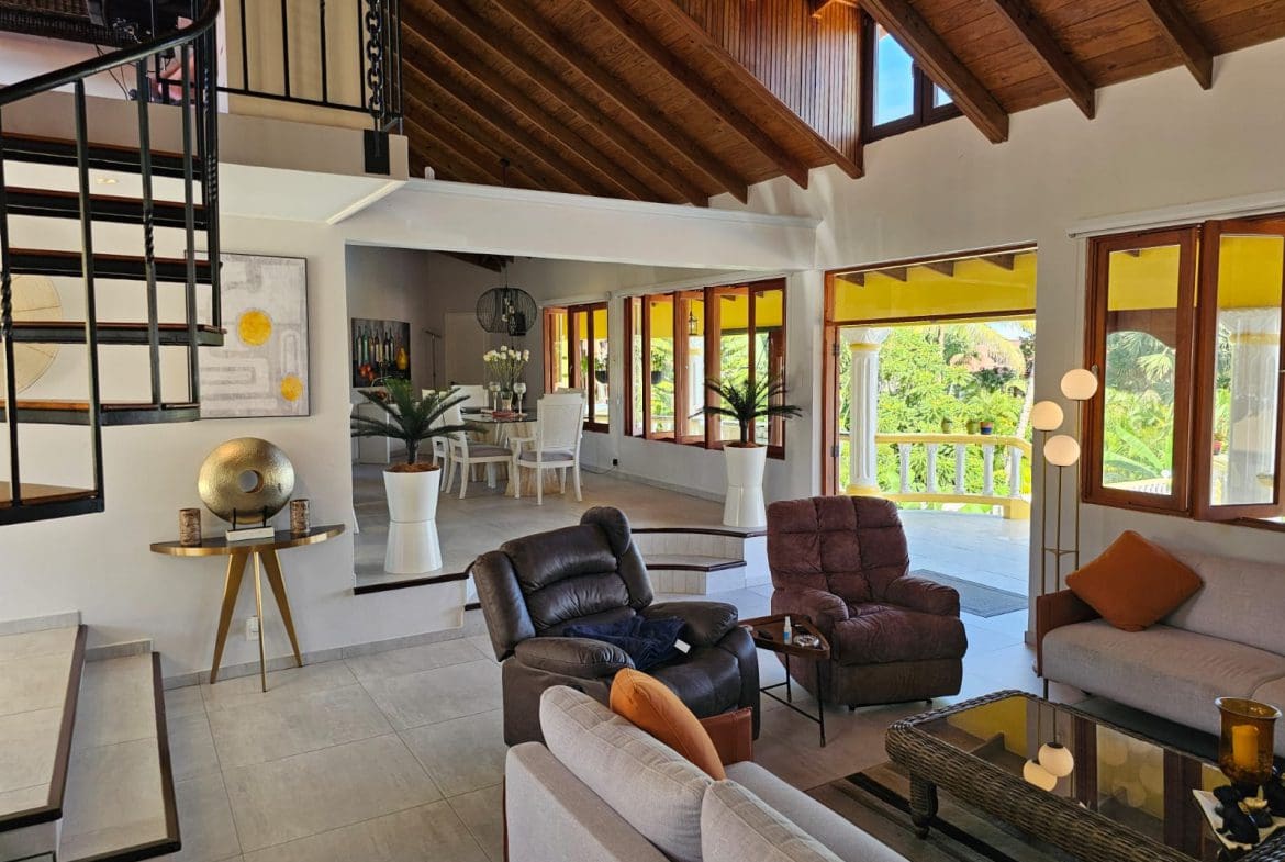 buyDRproperty Living area of a luxury villa with ocean views, featuring comfortable seating and a spiral staircase. Sosua Real Estate