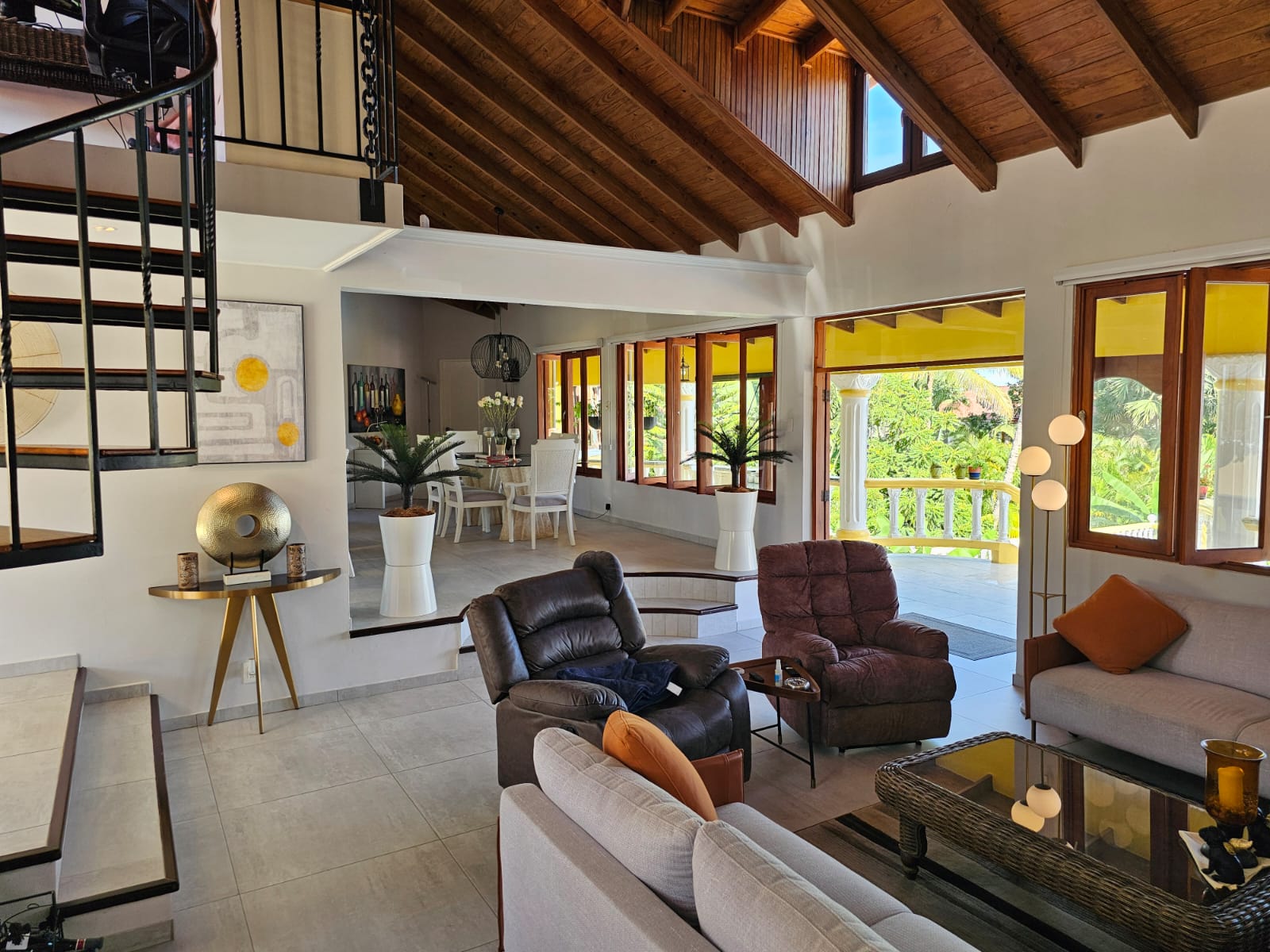 buyDRproperty Living area of a luxury villa with ocean views, featuring comfortable seating and a spiral staircase. Sosua Real Estate