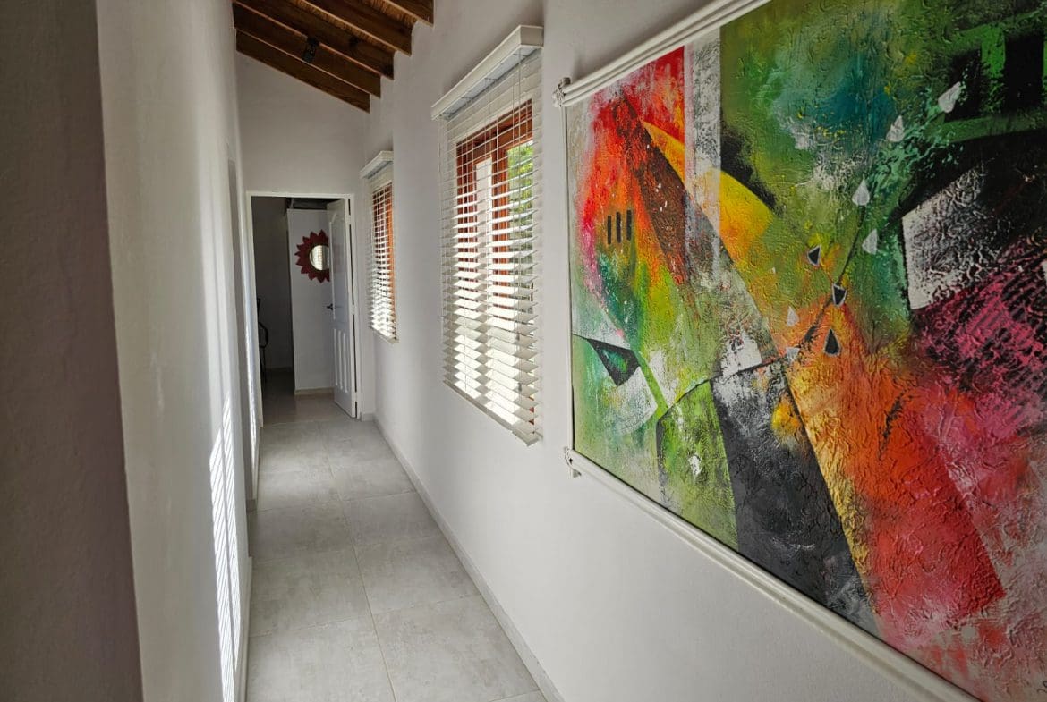 buyDRproperty Hallway in a luxury villa with modern art, tile floor, and windows. Villa for sale with ocean views. Sosua Real Estate