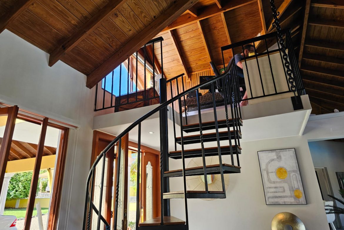 buyDRproperty Interior view of a luxury villa with a spiral staircase leading to a loft area with ocean views. Sosua Real Estate