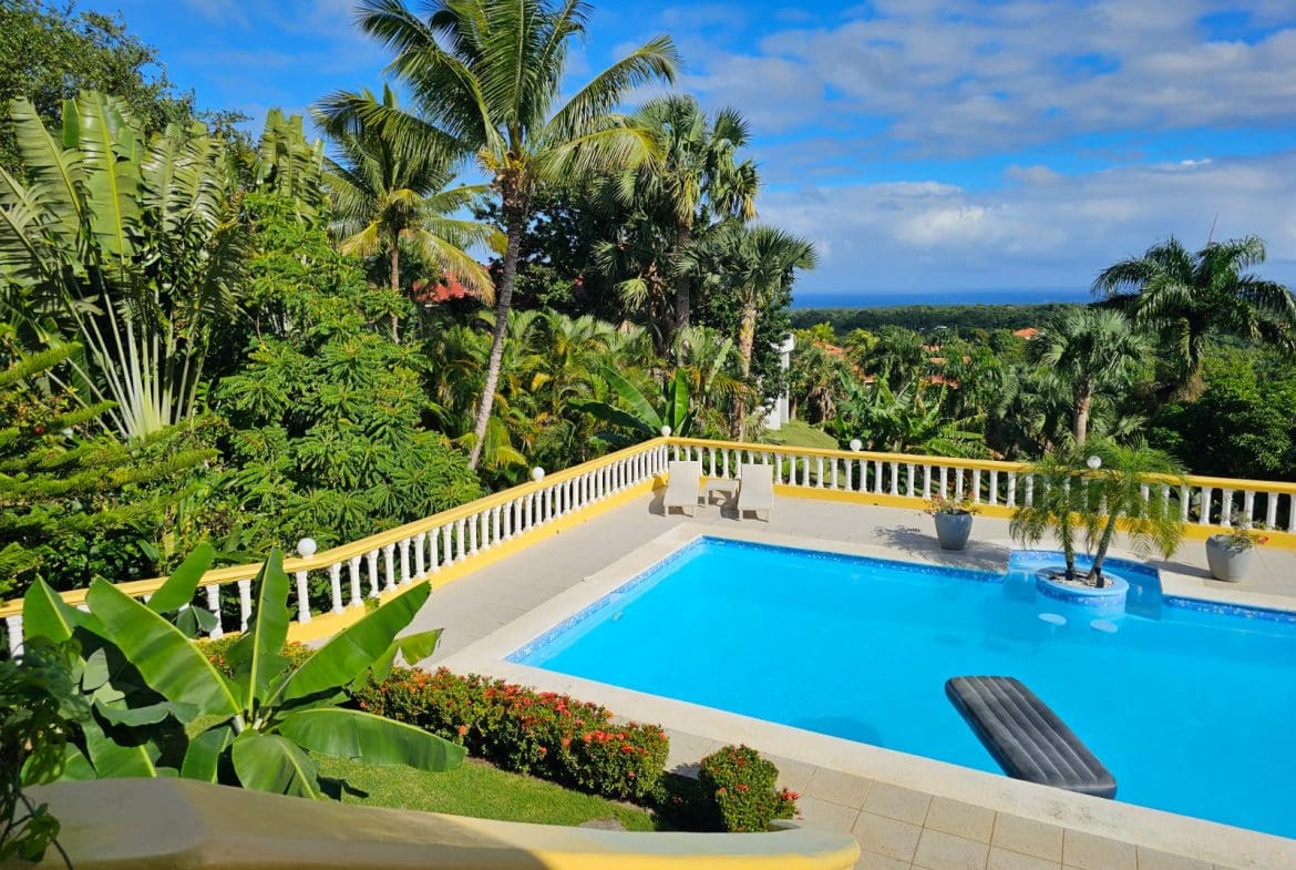 buyDRproperty Luxury villa swimming pool with ocean views, surrounded by lush tropical greenery. Villa for sale. Sosua Real Estate