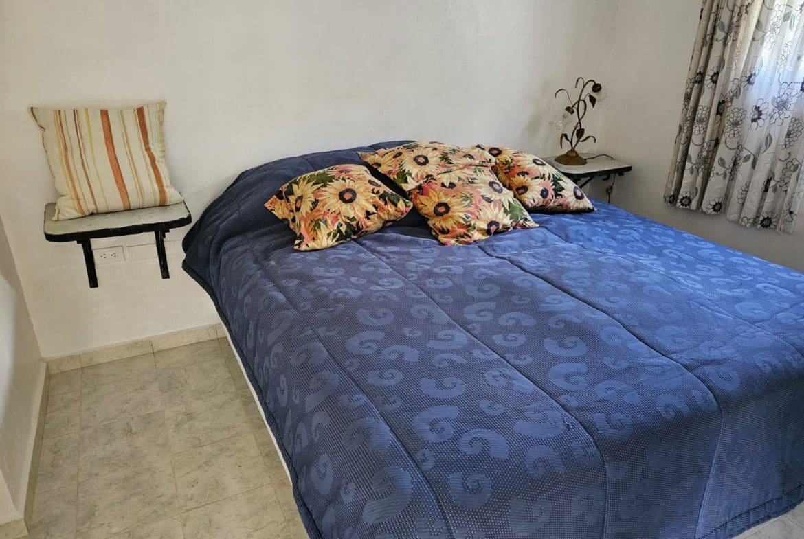buyDRproperty Bedroom in Ocean View Villa with blue bedding and floral pillows. Sosua Real Estate