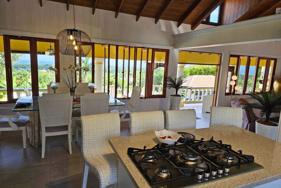 buyDRproperty Bright villa interior with dining area, kitchen island, and amazing ocean views. Villa for sale. Sosua Real Estate