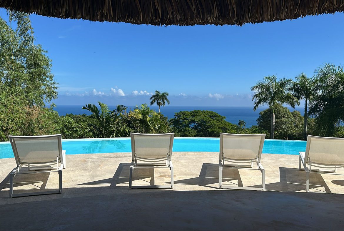 buyDRproperty Ocean view from villa for sale in Cabrera, Dominican Republic. Lounge chairs by the pool overlooking the ocean. Sosua Real Estate