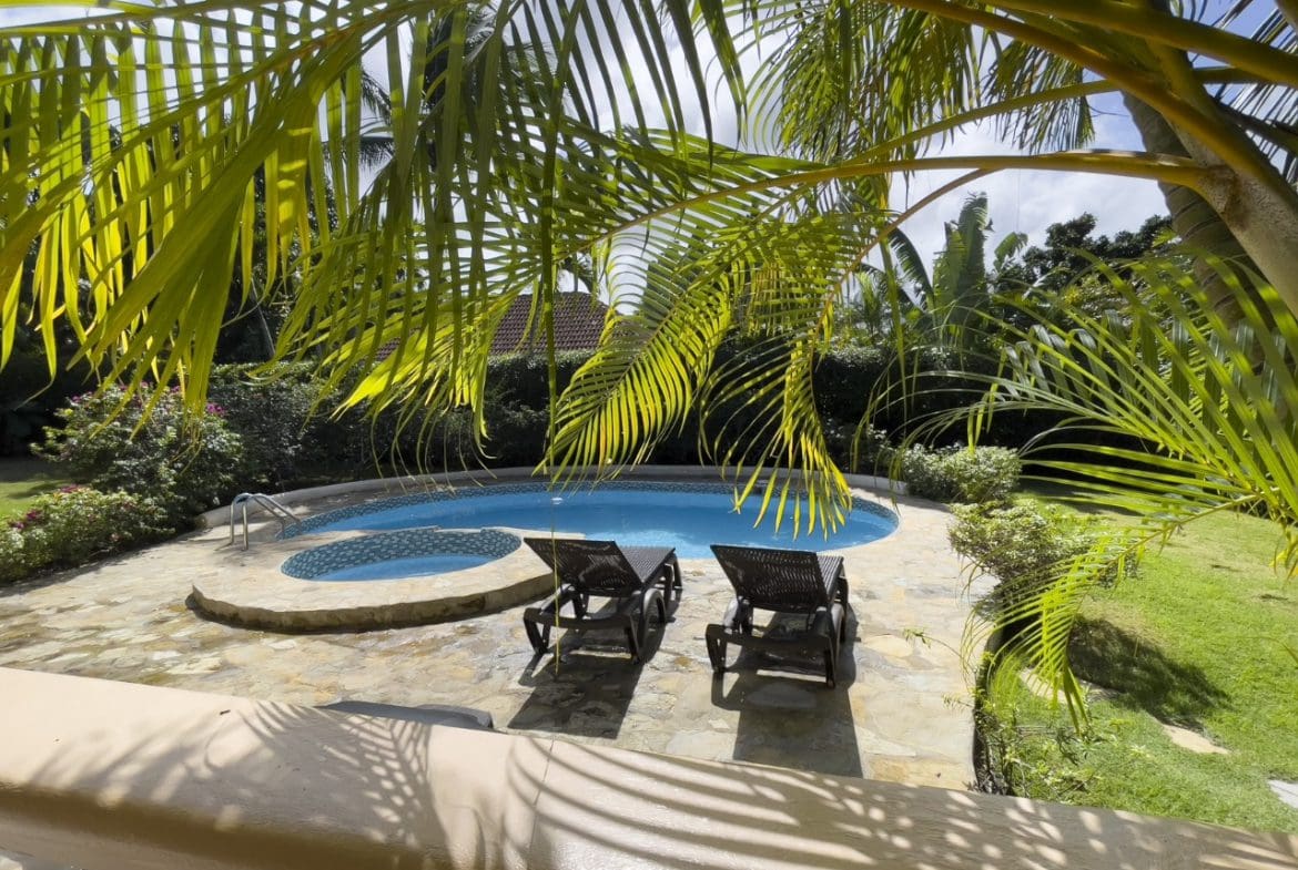 buyDRproperty Pool and lounge chairs at a 3BR Ocean View Home in Hispaniola, framed by palm trees. Sosua Real Estate
