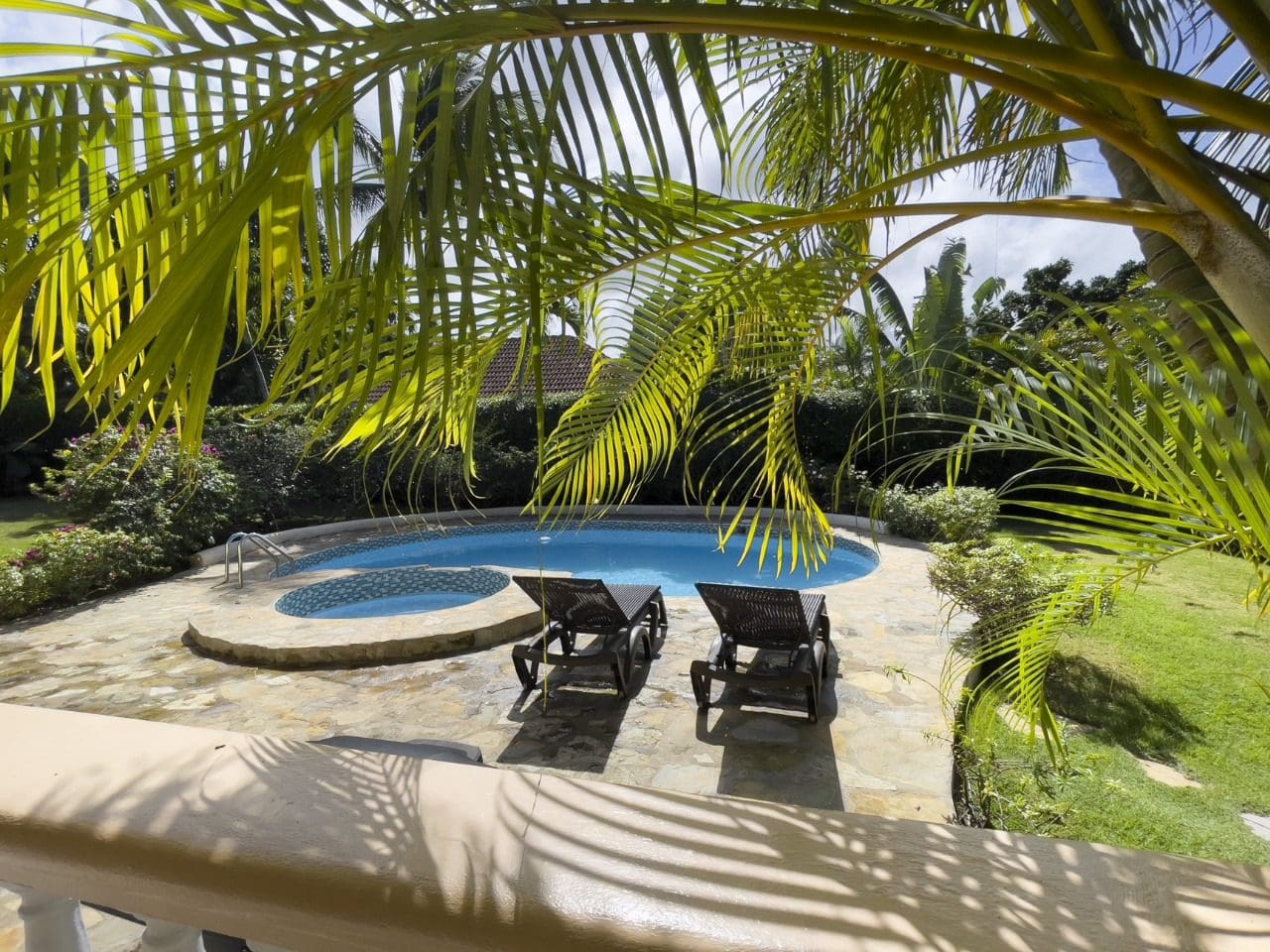 buyDRproperty Pool and lounge chairs at a 3BR Ocean View Home in Hispaniola, framed by palm trees. Sosua Real Estate