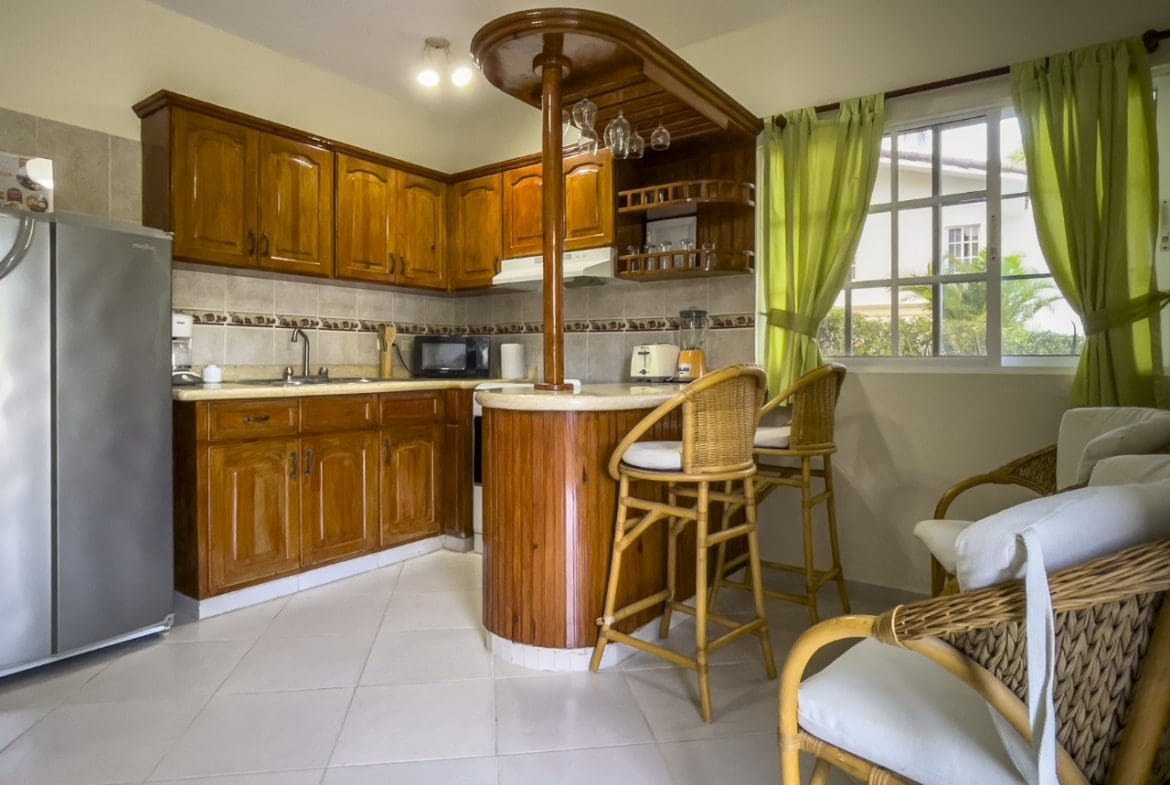 buyDRproperty Kitchen in 3BR Ocean View Home, Hispaniola, with wooden cabinets and bar seating. Sosua Real Estate