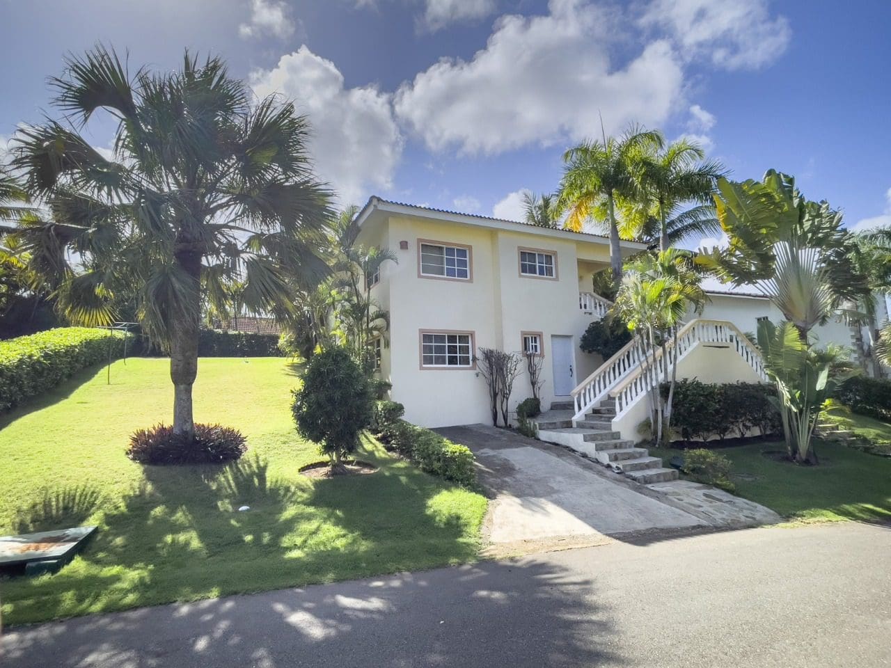 buyDRproperty 3BR Ocean View Home in Hispaniola with lush lawn and palm trees, showcasing tropical living. Sosua Real Estate