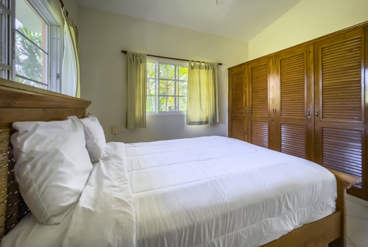buyDRproperty Bedroom with wooden bed frame and white linens in a 3BR Ocean View Home in Hispaniola. Sosua Real Estate