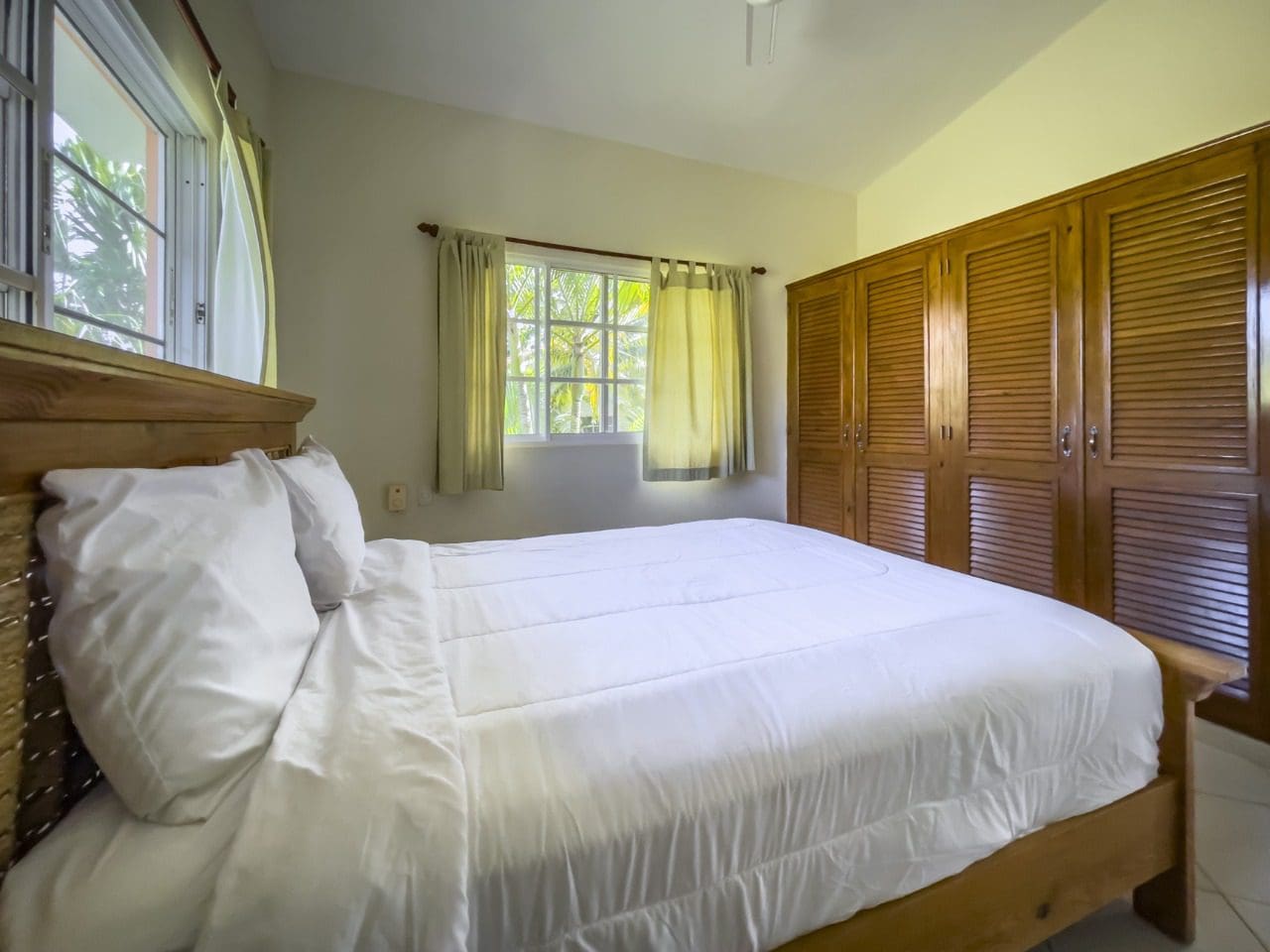 buyDRproperty Bedroom with wooden bed frame and white linens in a 3BR Ocean View Home in Hispaniola. Sosua Real Estate