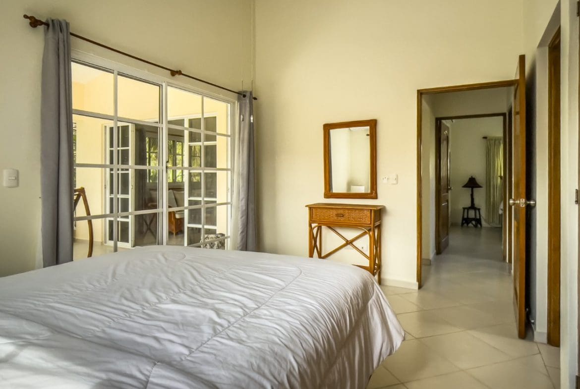buyDRproperty Bright bedroom in 3BR Ocean View Home with white bedding and a mirror. Sosua Real Estate