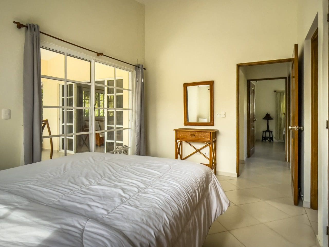 buyDRproperty Bright bedroom in 3BR Ocean View Home with white bedding and a mirror. Sosua Real Estate