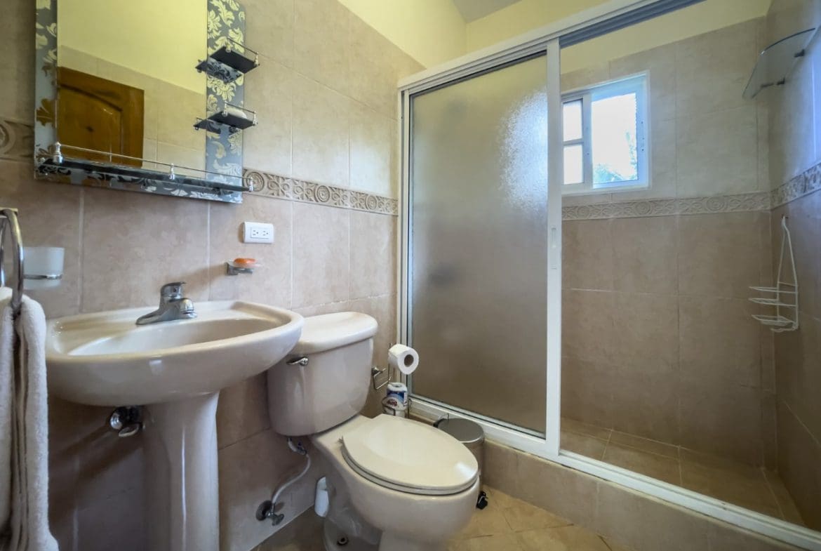 buyDRproperty Bathroom interior with sink, toilet, and glass-enclosed shower in a Hispaniola home. Sosua Real Estate