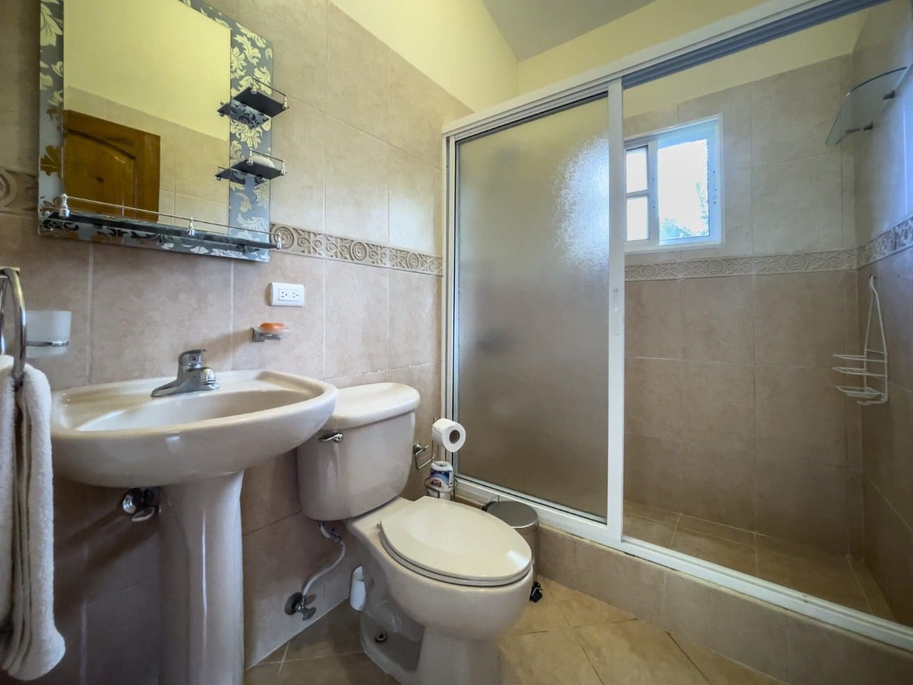 buyDRproperty Bathroom interior with sink, toilet, and glass-enclosed shower in a Hispaniola home. Sosua Real Estate