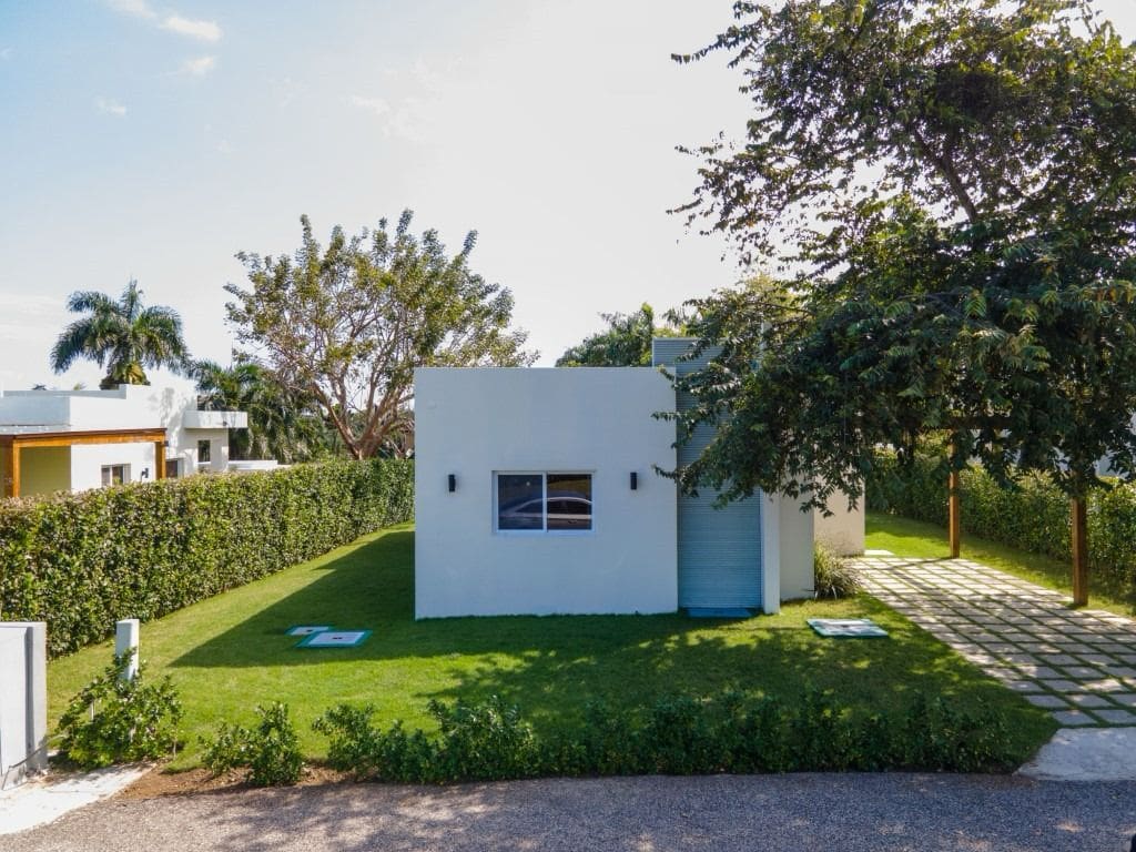 buyDRproperty Modern home for sale in Sosua, featuring a manicured lawn and gated community. Sosua Real Estate