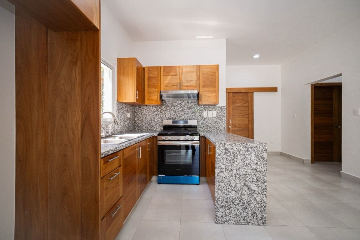 buyDRproperty Modern kitchen in a home for sale. Wooden cabinets, granite countertops, and stainless steel appliances. Sosua Real Estate