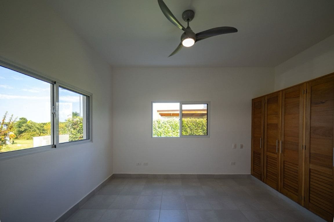 buyDRproperty Bright bedroom with large windows, a ceiling fan, and wood closet doors. Home for Sale. Sosua Real Estate
