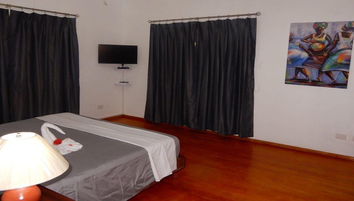 buyDRproperty Bedroom in Casa Linda villa with gray bedding, curtains, and artwork. Sosua Real Estate