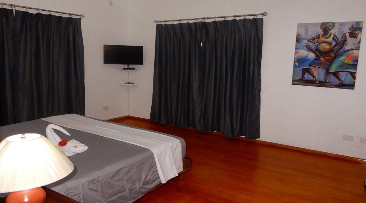 buyDRproperty Bedroom in Casa Linda villa with gray bedding, curtains, and artwork. Sosua Real Estate