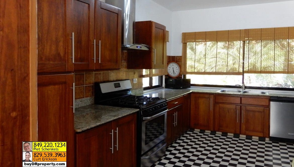buyDRproperty Kitchen in a Casa Linda villa for sale, featuring dark wood cabinets and a checkerboard floor. Sosua Real Estate