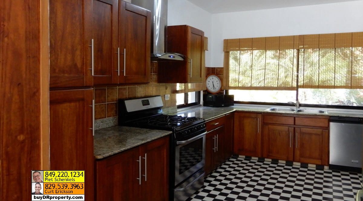 buyDRproperty Kitchen in a Casa Linda villa for sale, featuring dark wood cabinets and a checkerboard floor. Sosua Real Estate