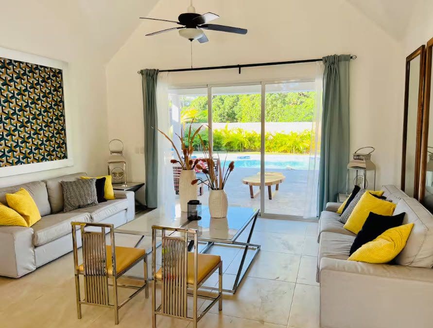 buyDRproperty Living room of a beautiful 9-bedroom villa featuring sofas, a coffee table, and a view of the pool and garden. Sosua Real Estate
