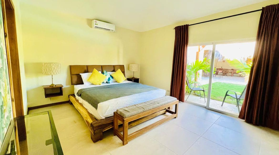 buyDRproperty Bedroom in a beautiful 9-bedroom villa with a king bed, bench, and patio access. Sosua Real Estate