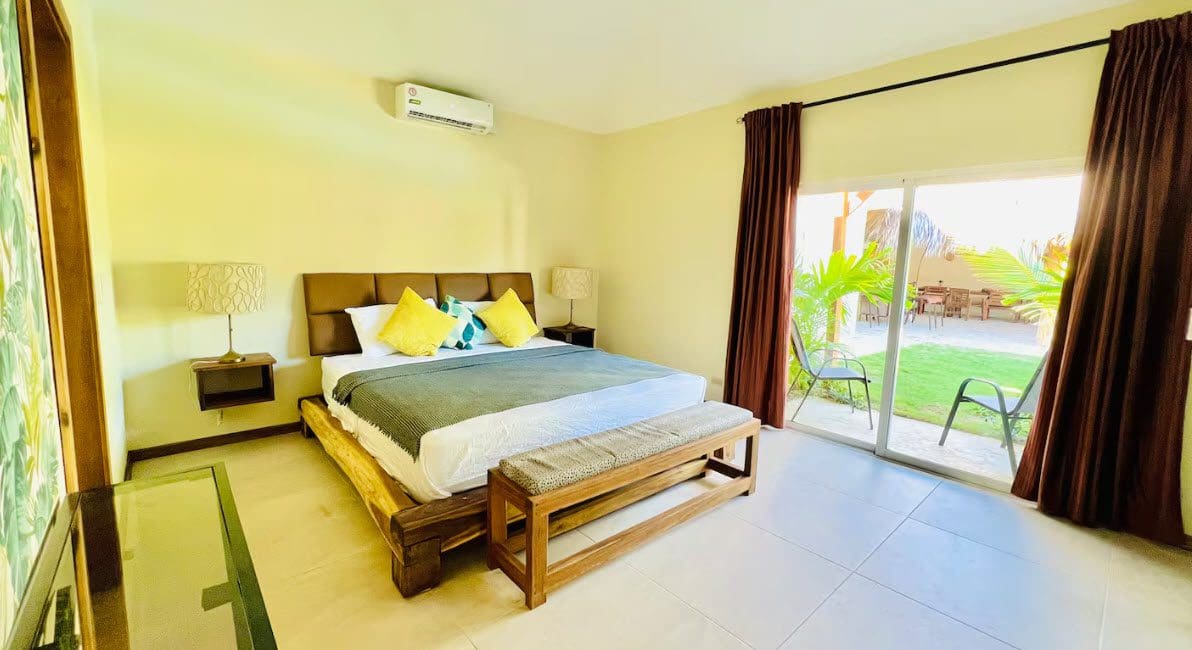 buyDRproperty Bedroom in a beautiful 9-bedroom villa with a king bed, bench, and patio access. Sosua Real Estate