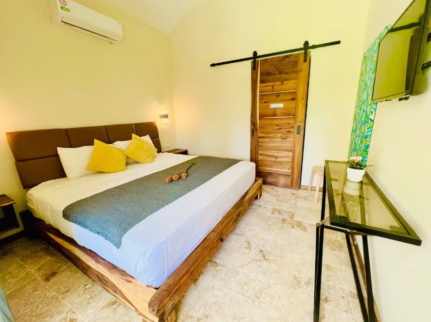 buyDRproperty Bedroom in a beautiful 9-bedroom villa with a king bed, sliding barn door, and modern decor. Sosua Real Estate